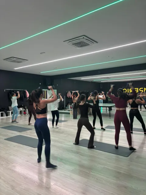 Clase grupal de fitness con mancuernas en estudio con iluminación neón verde
